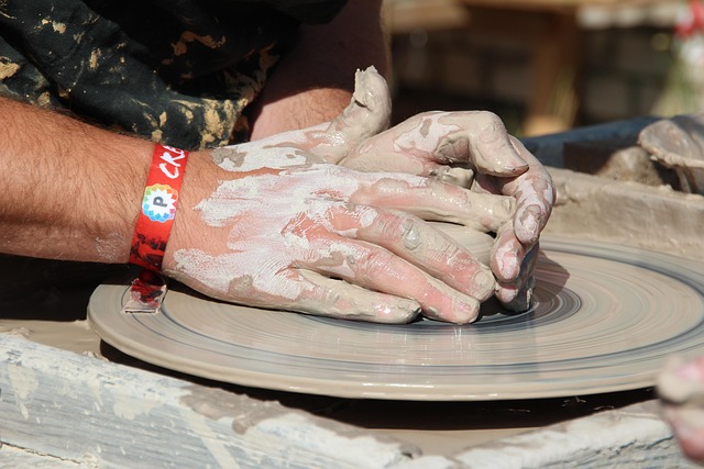 artisan hands shaping clay bowl on pottery wheel in warm studio light